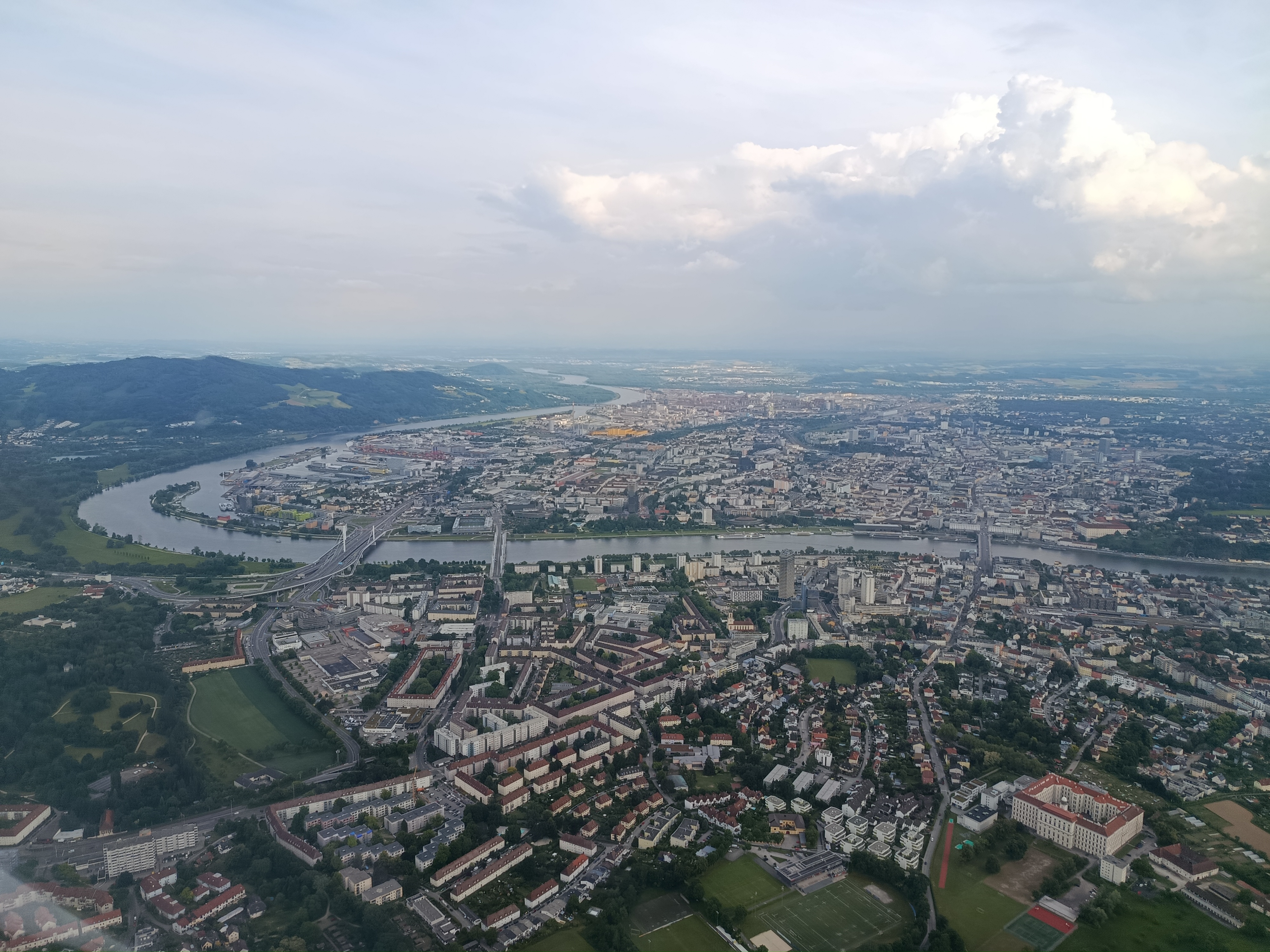 Linz und Urfahr von Urfahr aus betrachtet. Links kann man den Pfenningberg erkennen, an welchem die Donau entlang fließt. Gegenüber davon der Flugplatz Linz-Ost.